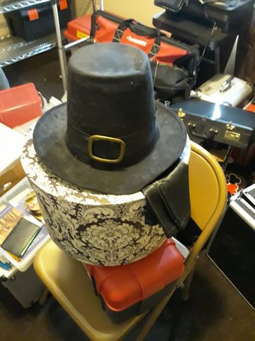 A black top hat resting on a decorative hat box amid storage bins